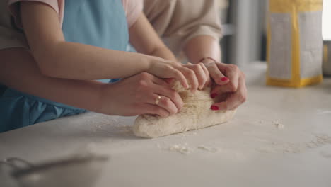 kneading-dough-in-home-kitchen-mother-and-daughter-are-making-pastry-for-bread-mom-is-teaching-her-child-cooking